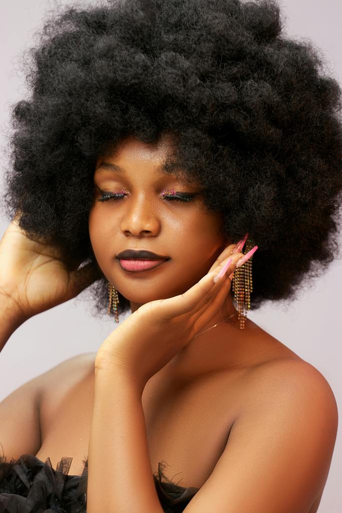 Studio portrait of a stylish woman with afro hair and glamorous makeup.
